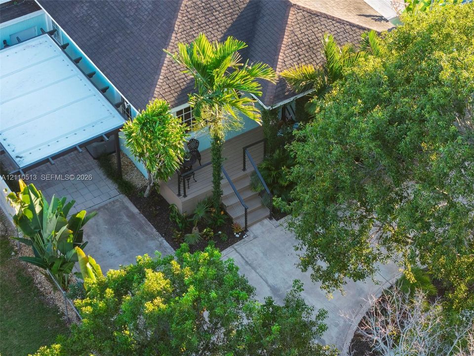 Exterior features include a concrete driveway, a covered parking structure, a wooden front deck with stairs, and mature landscaping