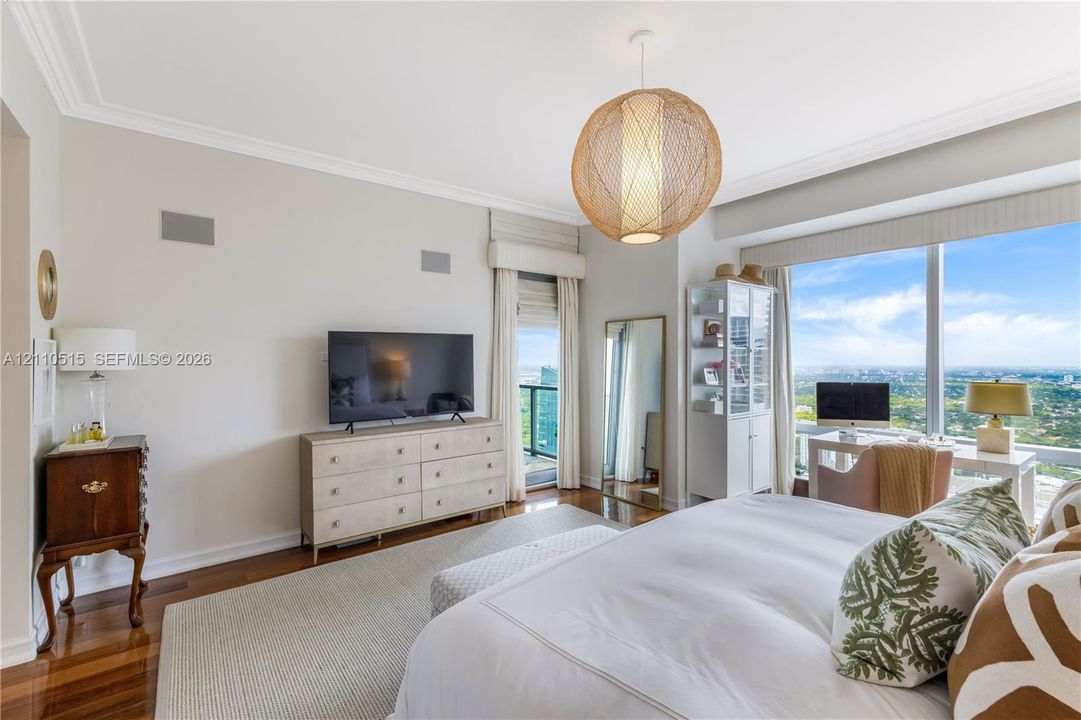 Floor-to-ceiling windows, wood-finish flooring, crown molding, spherical pendant lighting, and private balcony access