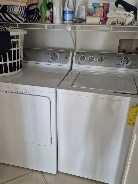 Laundry area featuring side-by-side appliances and wire shelving