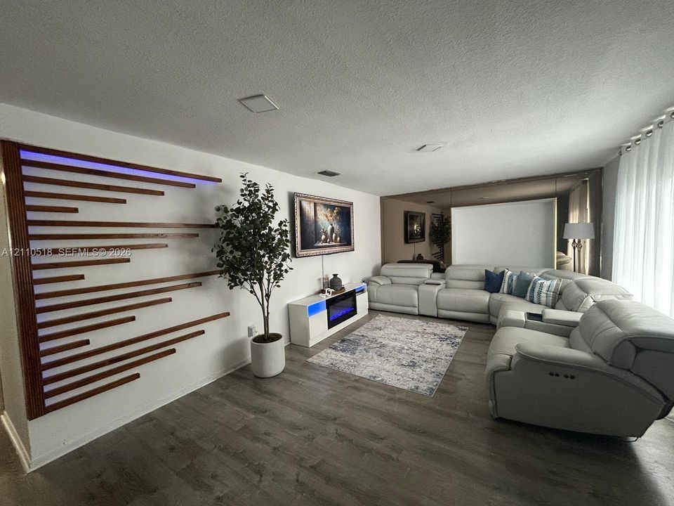 Living area featuring wood-finish flooring, a custom horizontal slat accent wall with integrated LED lighting, and a mirrored wall panel
