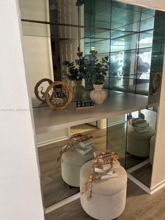 Wall-to-wall mirrored paneling featuring a built-in floating shelf and wood-finish flooring