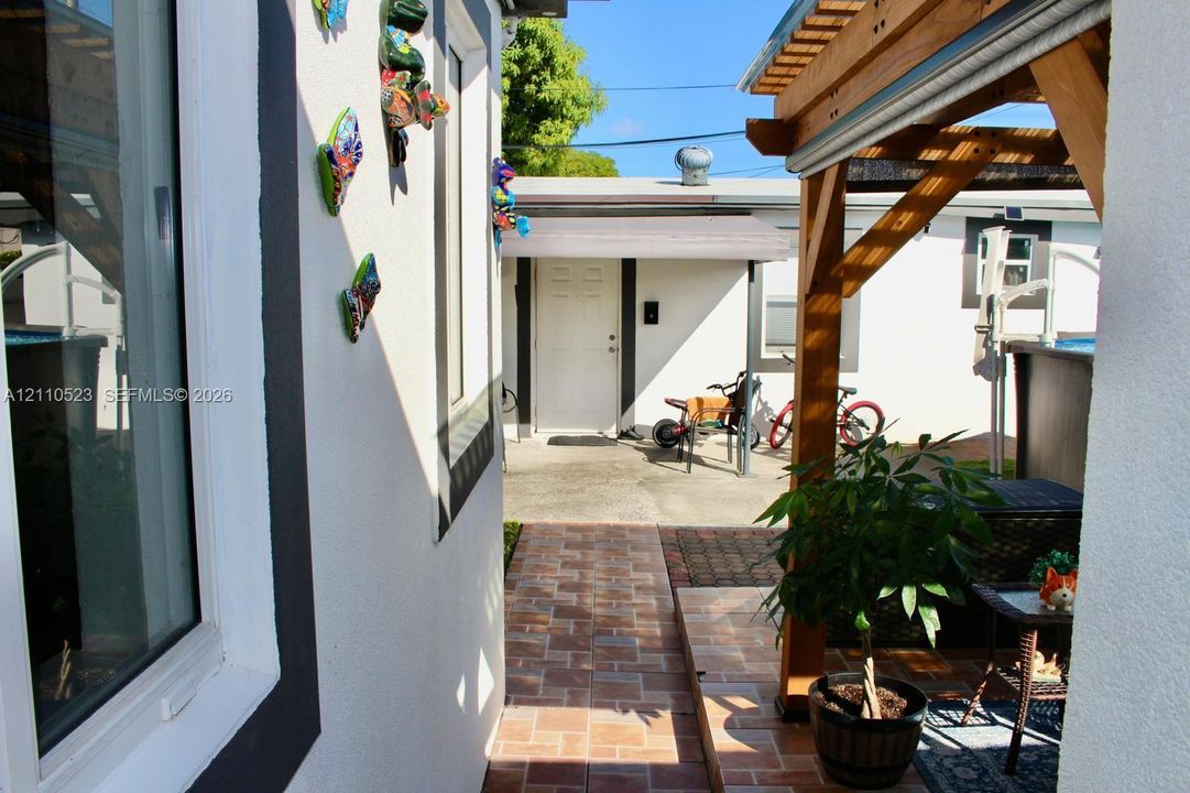 Exterior walkway featuring decorative stone-finish tile pavers and a natural wood-finish pergola structure