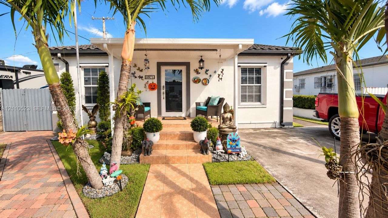 Exterior facade featuring a covered front porch, tile entryway steps, concrete driveway, and paver walkway