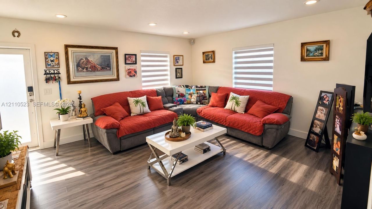 Living area featuring wood-finish flooring, recessed lighting, and dual windows with integrated shades