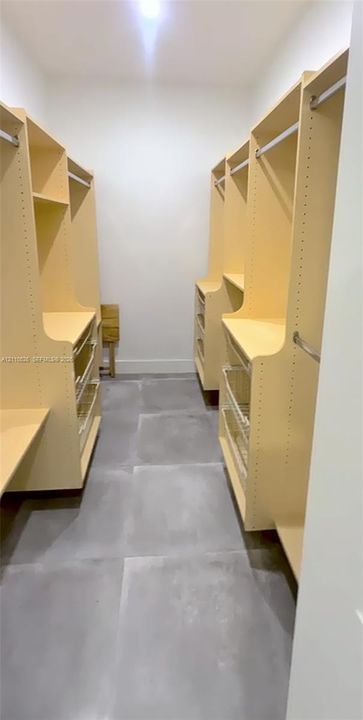 Customized storage system featuring built-in shelving, hanging rods, and integrated pull-out drawers, complemented by large-format tile flooring