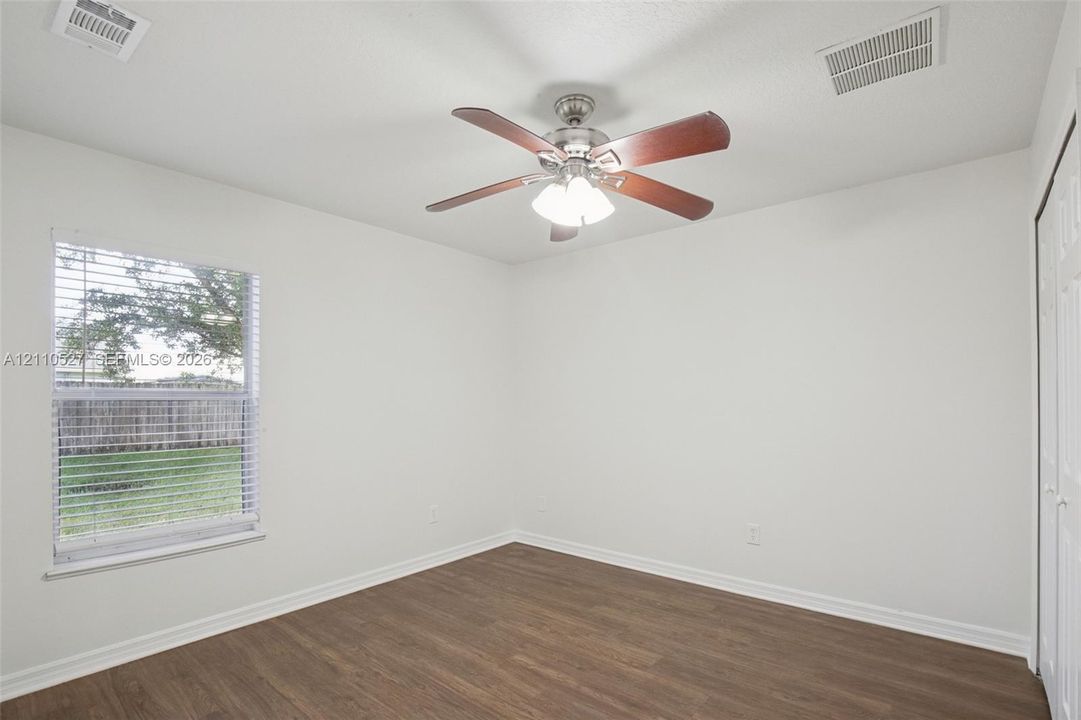 Interior space featuring wood-finish flooring, a ceiling fan with integrated lighting, and a single window with horizontal blinds