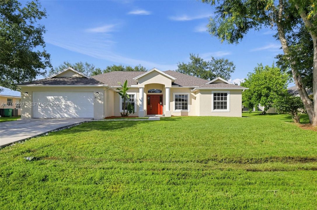 Single-story residence featuring a stucco exterior, covered entryway with arched columns, multi-pane windows, double-car garage, and mature landscaping