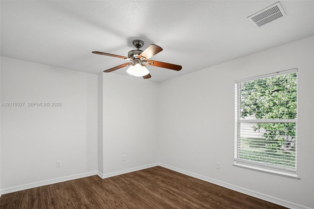 Room featuring wood-finish flooring, a neutral color palette, a ceiling fan with integrated lighting, and a window with horizontal blinds