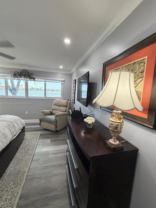 Interior space featuring wood-finish flooring, crown molding, recessed lighting, and large windows with water exposure