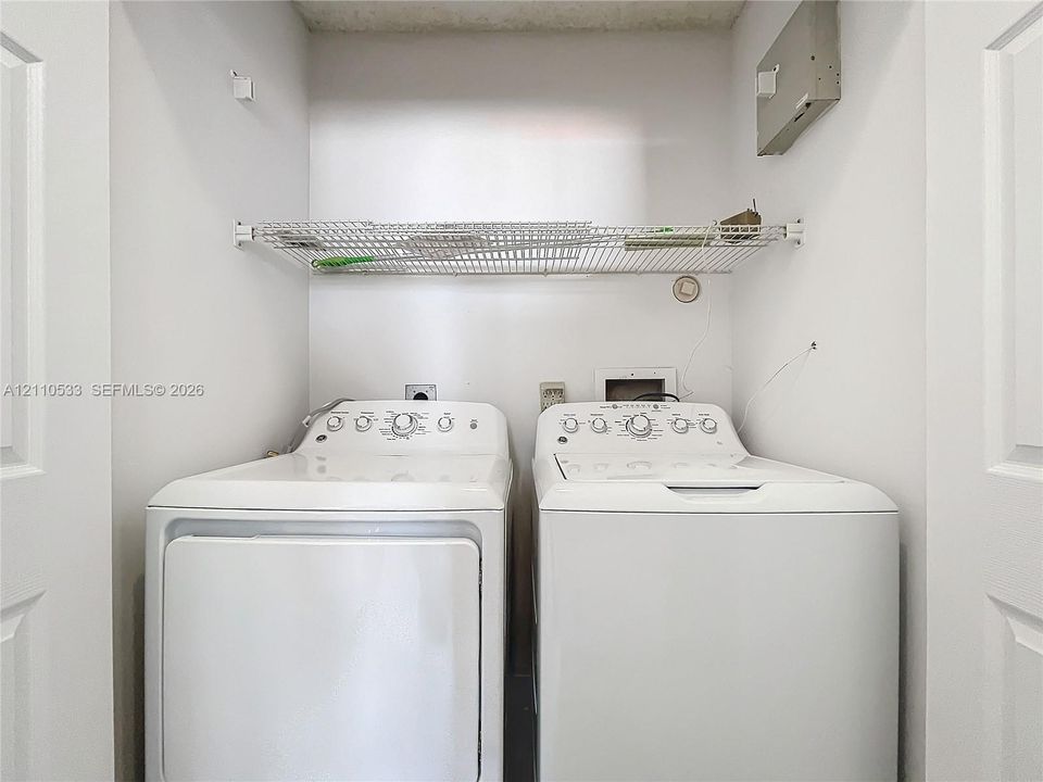 Laundry area featuring white appliance hookups and a mounted wire shelving unit