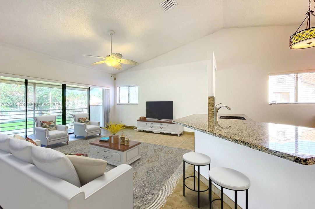 Vaulted ceilings, stone-surface breakfast bar, sliding glass doors, ceiling fan, and tile flooring