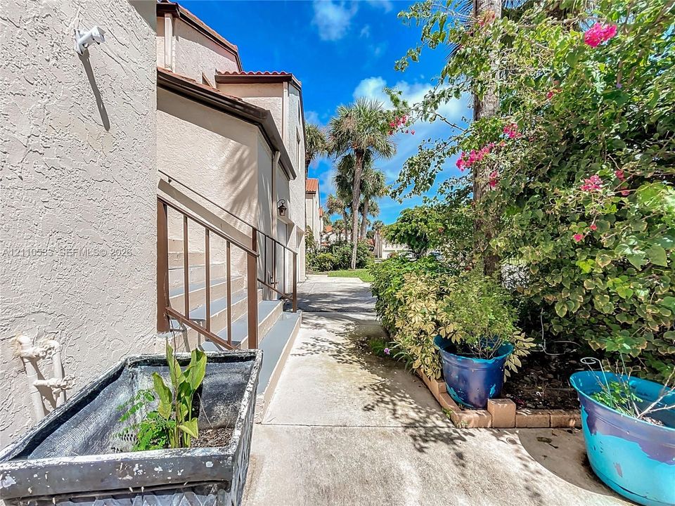 Stucco exterior featuring metal stair railings and a paved walkway