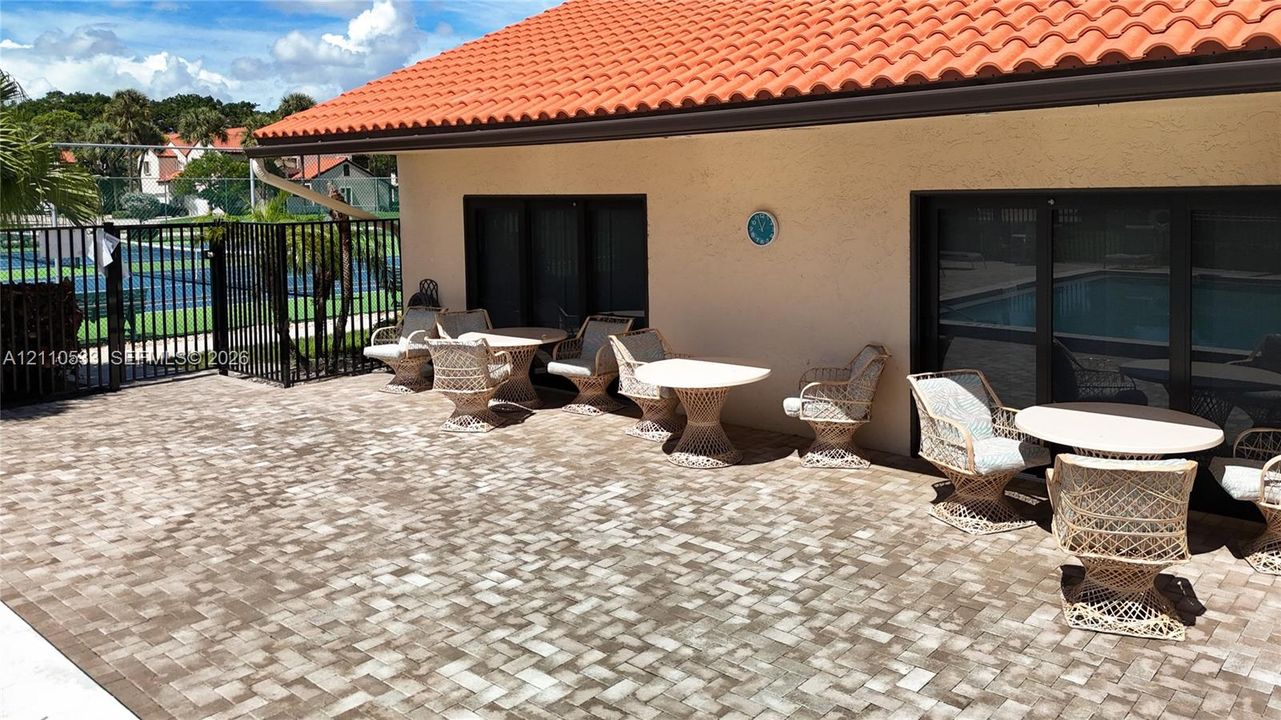 Spacious patio featuring stone-paver flooring, a tile roof, and black metal fencing