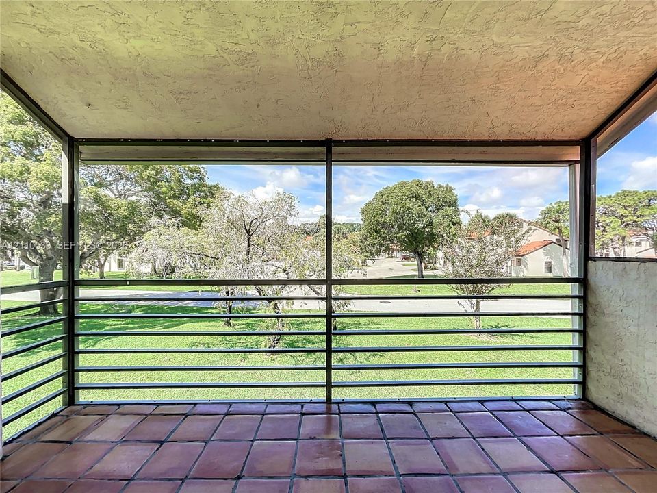 Screened-in balcony featuring tile flooring, metal railings, and a textured ceiling