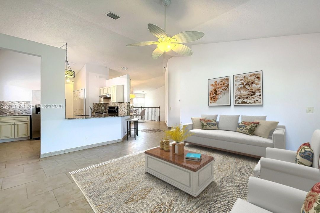 Vaulted ceilings, large-format tile flooring, kitchen featuring stone-surfaced breakfast bar, and decorative ceiling fan