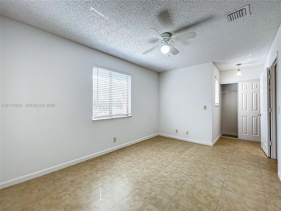 Neutral-toned tile flooring, ceiling fan with integrated lighting, and a closet with a paneled door