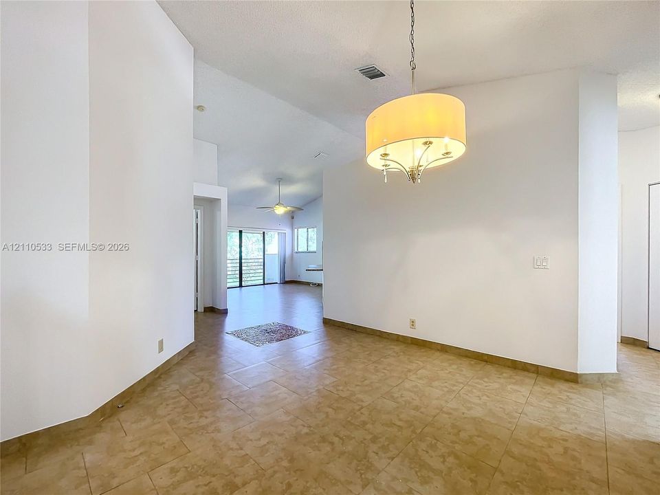 High-ceiling interior space featuring large-format tile flooring and a drum-style pendant light fixture
