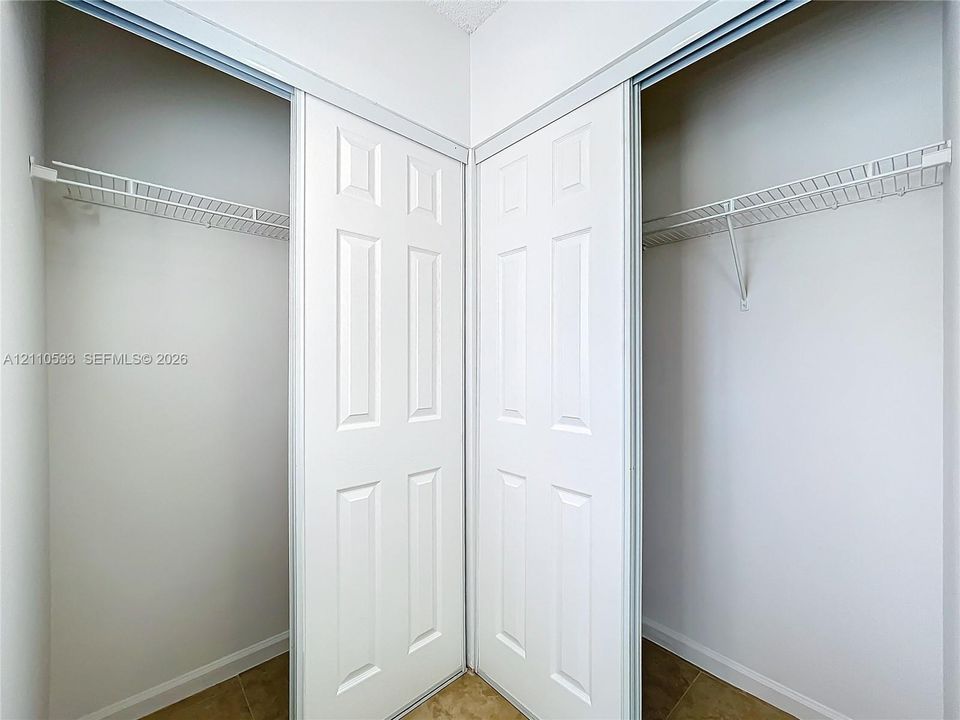 Dual reach-in closets featuring white six-panel sliding doors and integrated metal shelving