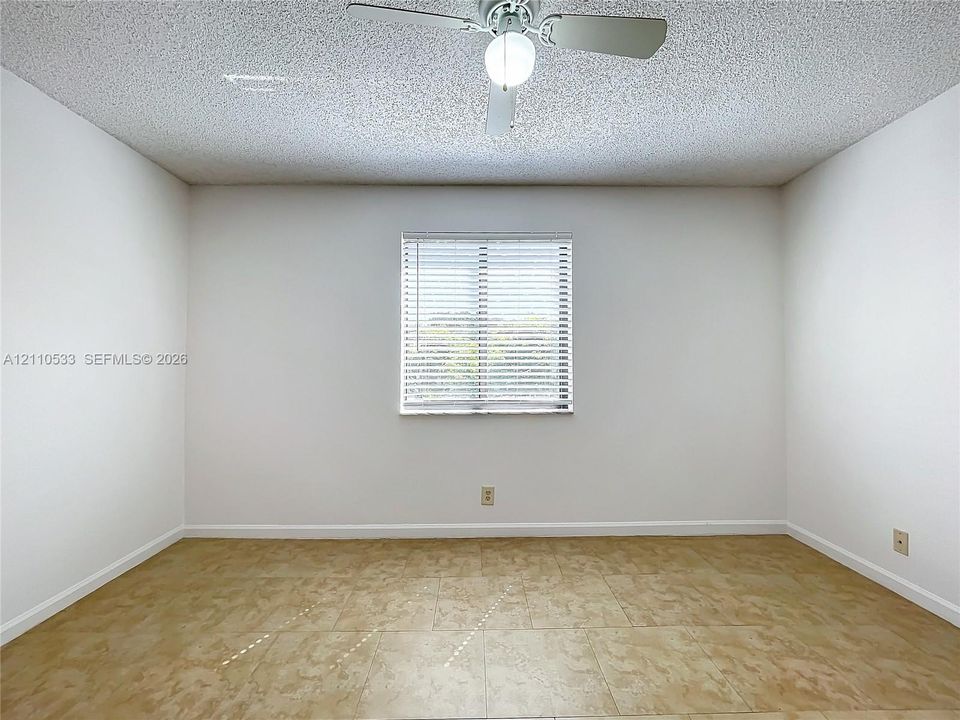 Interior space featuring tile flooring, a centered ceiling fan with integrated lighting, and a window fitted with horizontal blinds