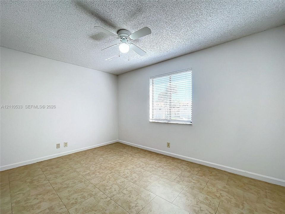 Interior room featuring neutral wall finishes, tile flooring, a white ceiling fan with integrated lighting, and a single window with horizontal blinds