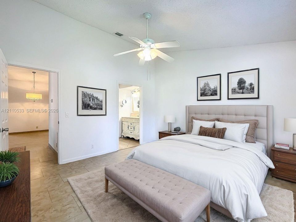 Vaulted ceilings, large-format tile flooring, and a central ceiling fan