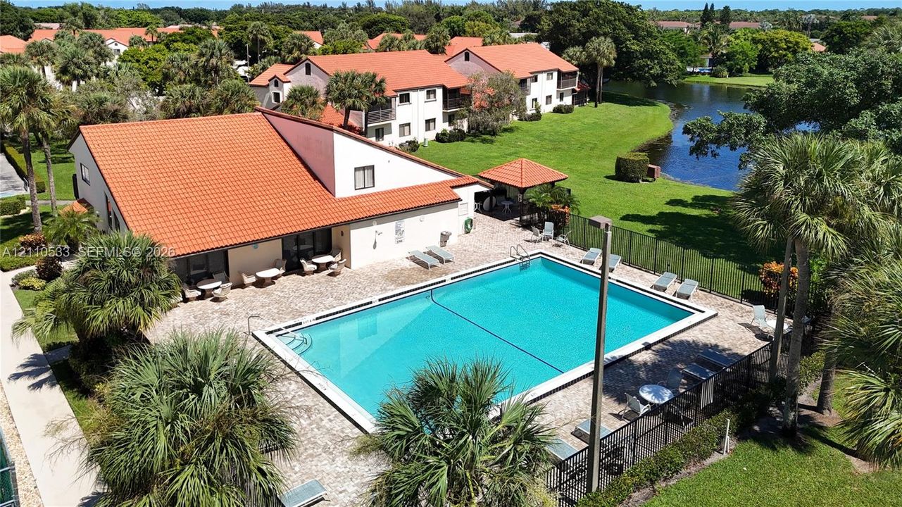 Community recreation area featuring an expansive swimming pool, paved patio, covered pavilion, and water frontage