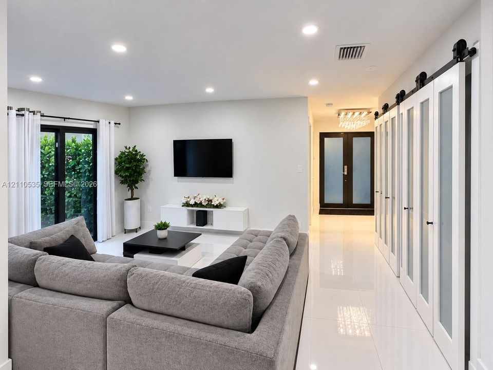 Interior featuring polished tile flooring, recessed ceiling lighting, and a series of white sliding doors with frosted glass panels and matte black hardware
