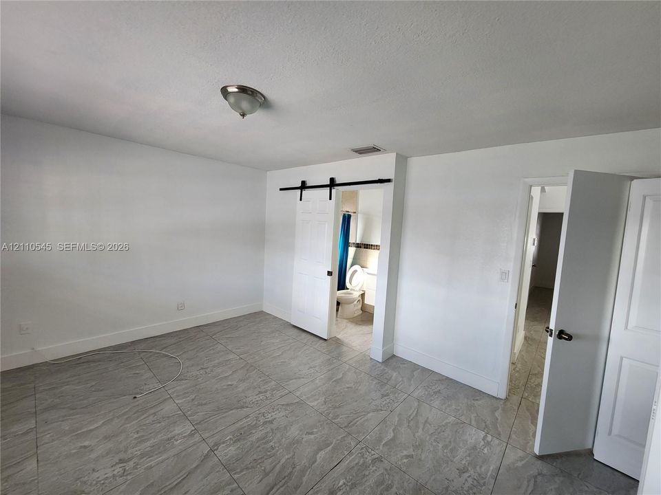 Interior space featuring oversized stone-finish floor tiles, a sliding barn-style door, and a flush-mount light fixture