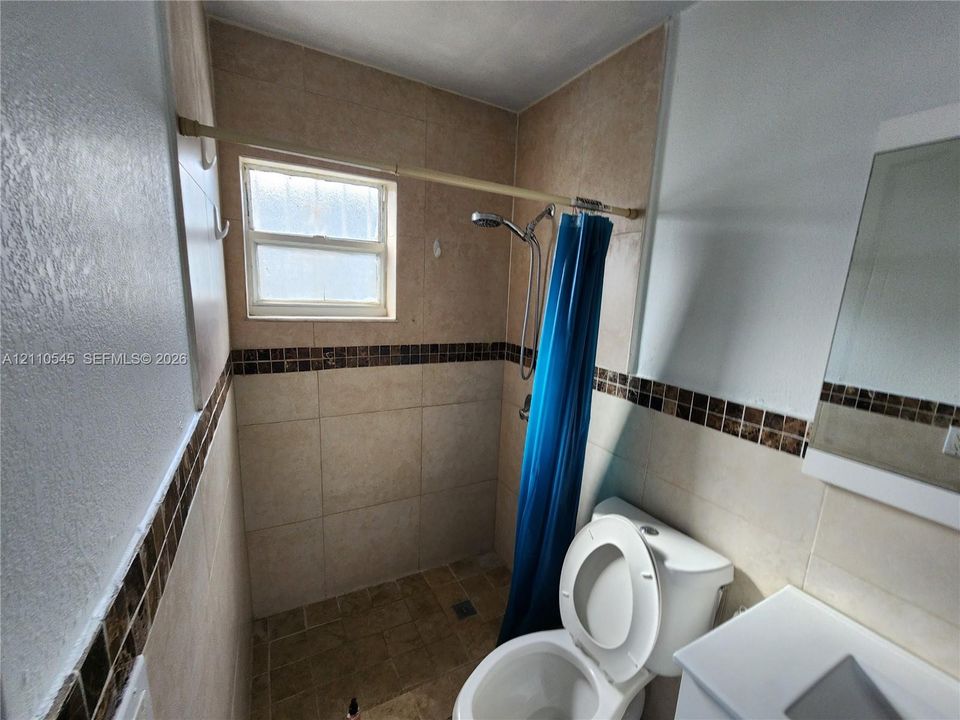 Bathroom featuring neutral large-format wall tile, mosaic tile inlay, vanity with an integrated basin, and a window with frosted glass