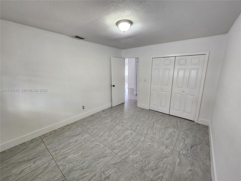 Large-format tile flooring, flush-mount ceiling lighting, and double-door closet cabinetry