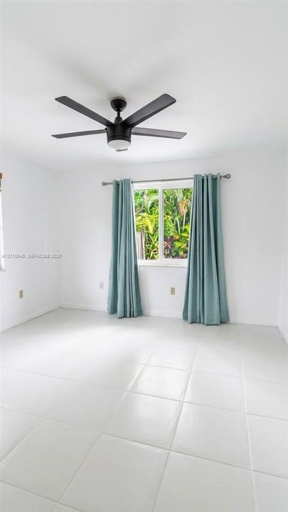 Neutral-toned tiled flooring, clean white wall finishes, and a matte black five-blade ceiling fan with integrated lighting