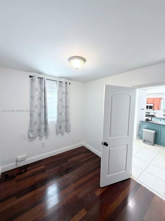 Room featuring dark wood-finish flooring, a neutral wall palette, and a multi-panel interior door