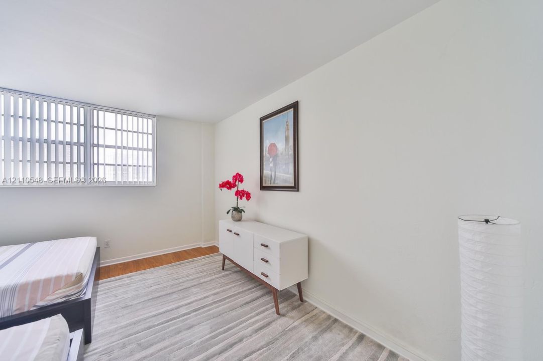 Interior space featuring neutral wall paint, wood-finish flooring, and horizontal window blinds