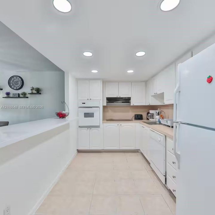 Kitchen featuring white cabinetry, recessed lighting, tile flooring, integrated wall oven, and a peninsula counter