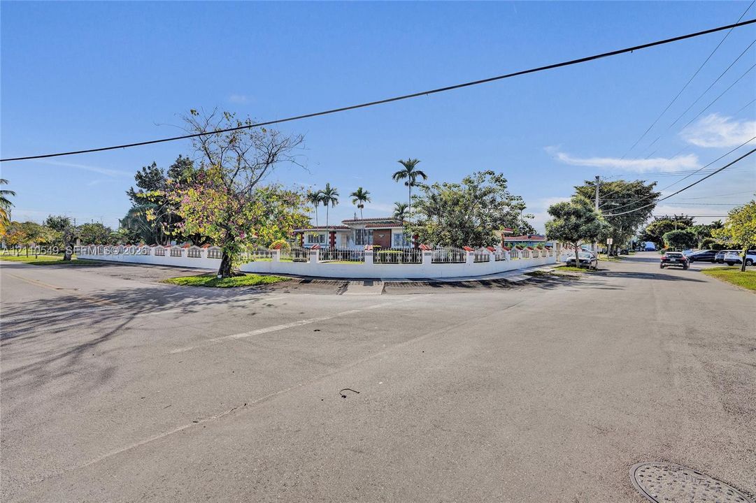 Corner lot property featuring a masonry perimeter wall, integrated metal fencing, and mature landscaping