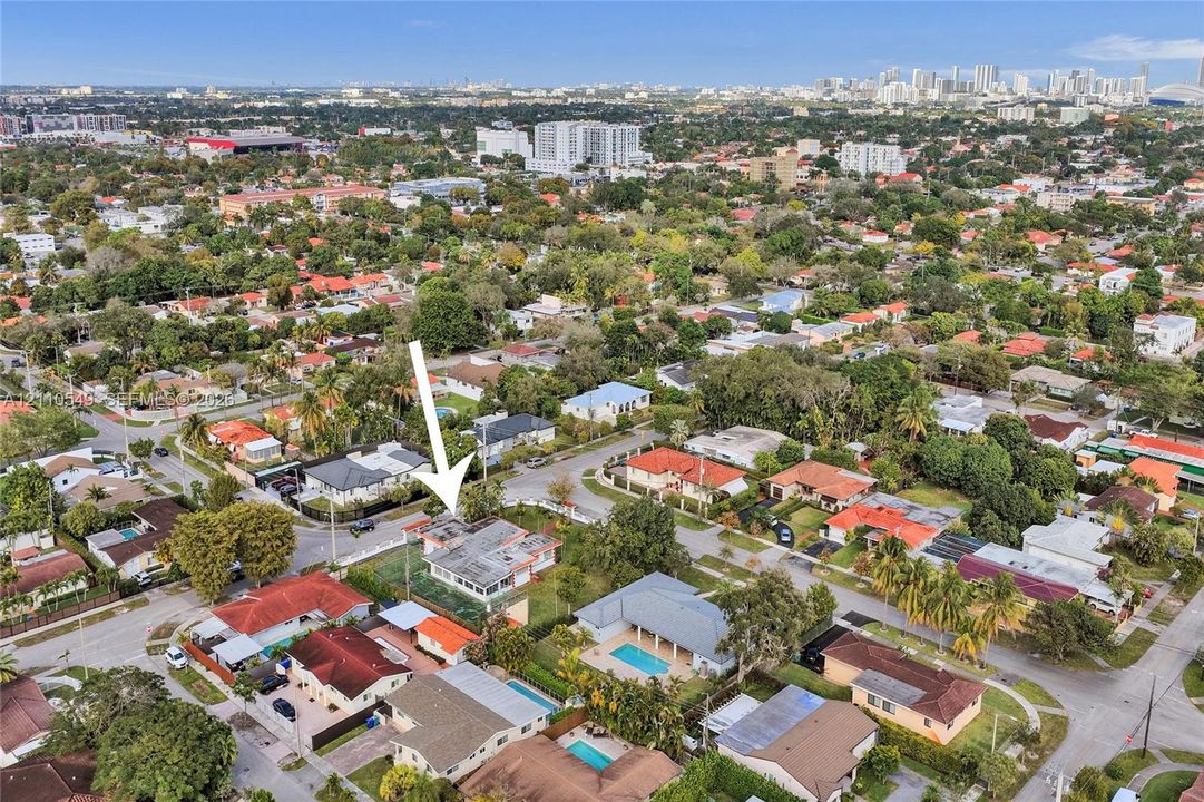 Aerial perspective of a corner lot residence featuring a screened-in rear patio, mature landscaping, and a fenced yard