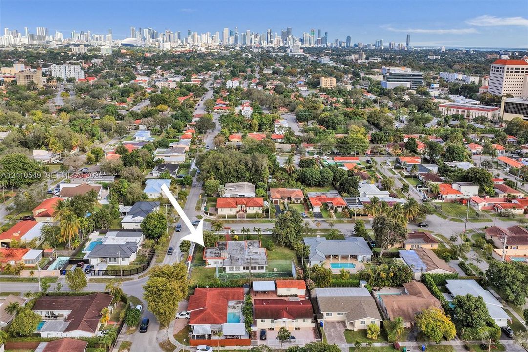 Aerial perspective of residential property featuring a flat-roof structure, expansive lot, and proximity to the urban skyline