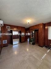 Wood-panelled interior walls, neutral tile flooring, mirrored closet doors, and a ceiling-mounted light fixture
