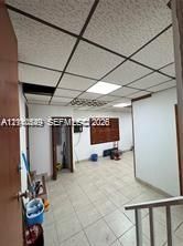 Interior space featuring grid-pattern acoustic drop ceiling tiles, integrated recessed lighting, and light-toned ceramic tile flooring