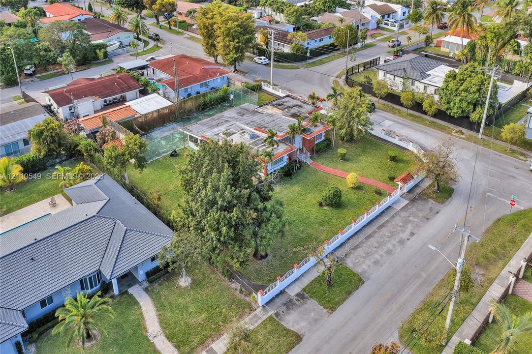 Corner lot residence featuring a fenced yard, private tennis court, mature trees, and a paved walkway