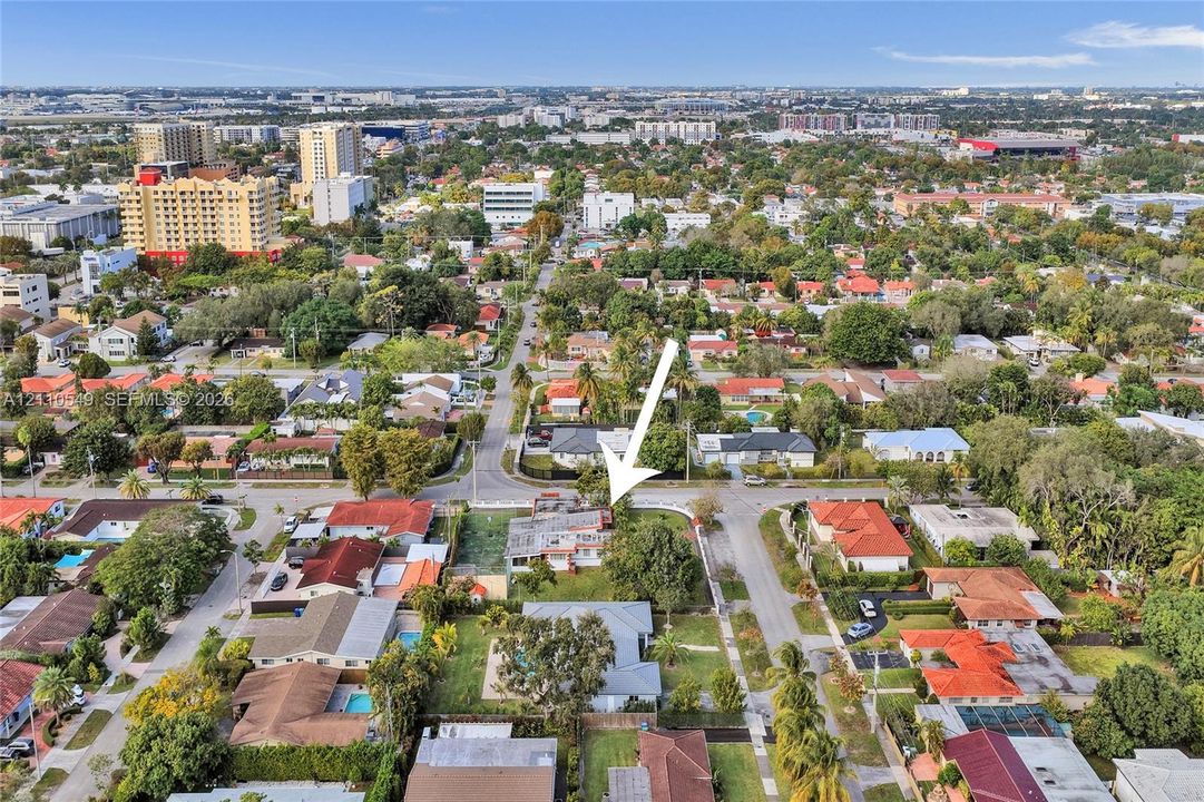 Aerial perspective of a corner lot property featuring a rectangular-shaped structure, perimeter fencing, and mature trees