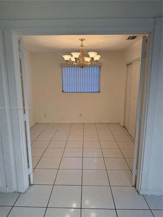 Neutral-tone tile flooring, multi-arm chandelier, and sliding closet doors