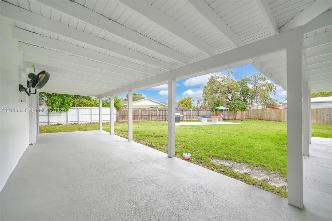 Covered patio featuring an exposed-beam ceiling, concrete flooring, and a fenced backyard