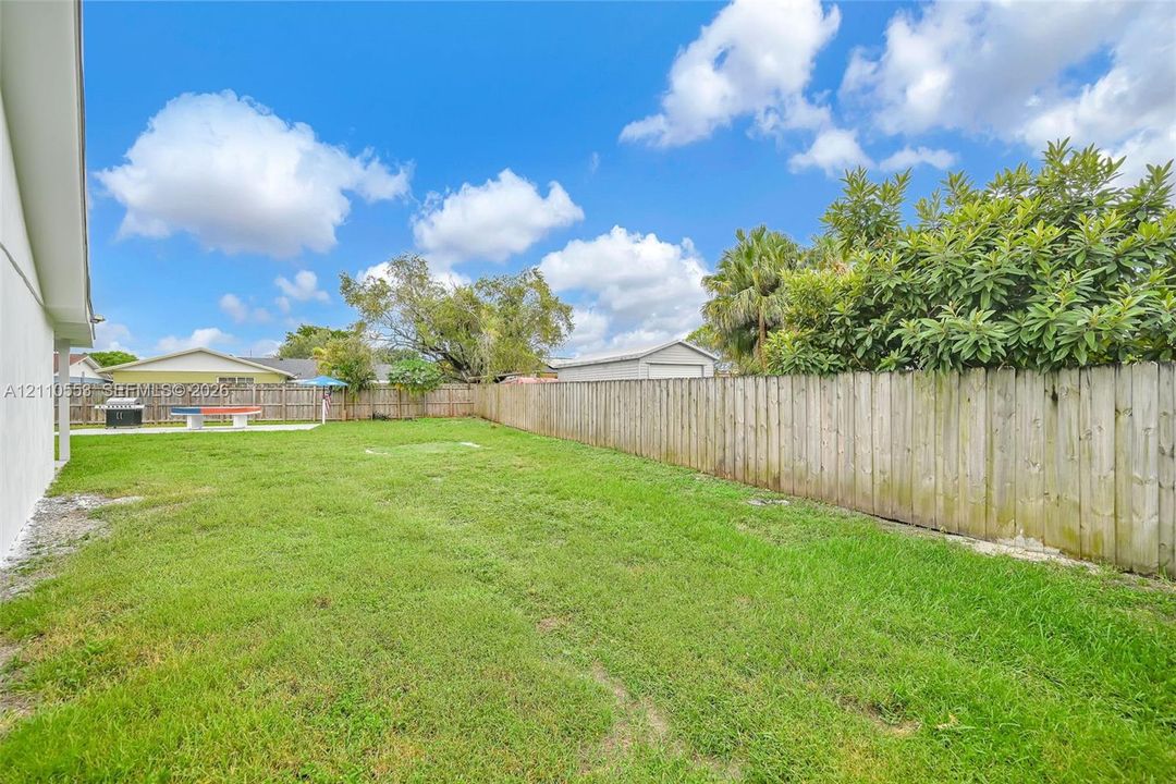 Expansive backyard featuring a level lawn, full-perimeter wood fencing, and mature landscaping