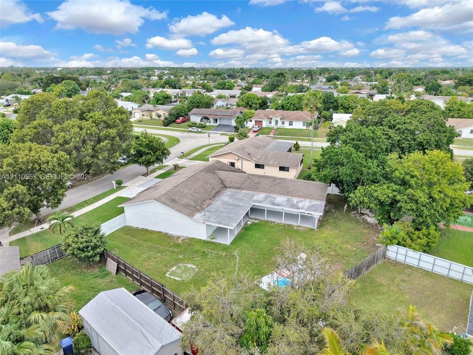 Single-story residence featuring a shingle roof, rear-facing covered patio, fenced backyard, and a detached storage structure
