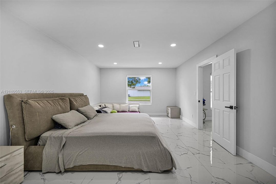 Interior room featuring large-format tile flooring with veining, recessed lighting, and a multi-panel door with matte black hardware