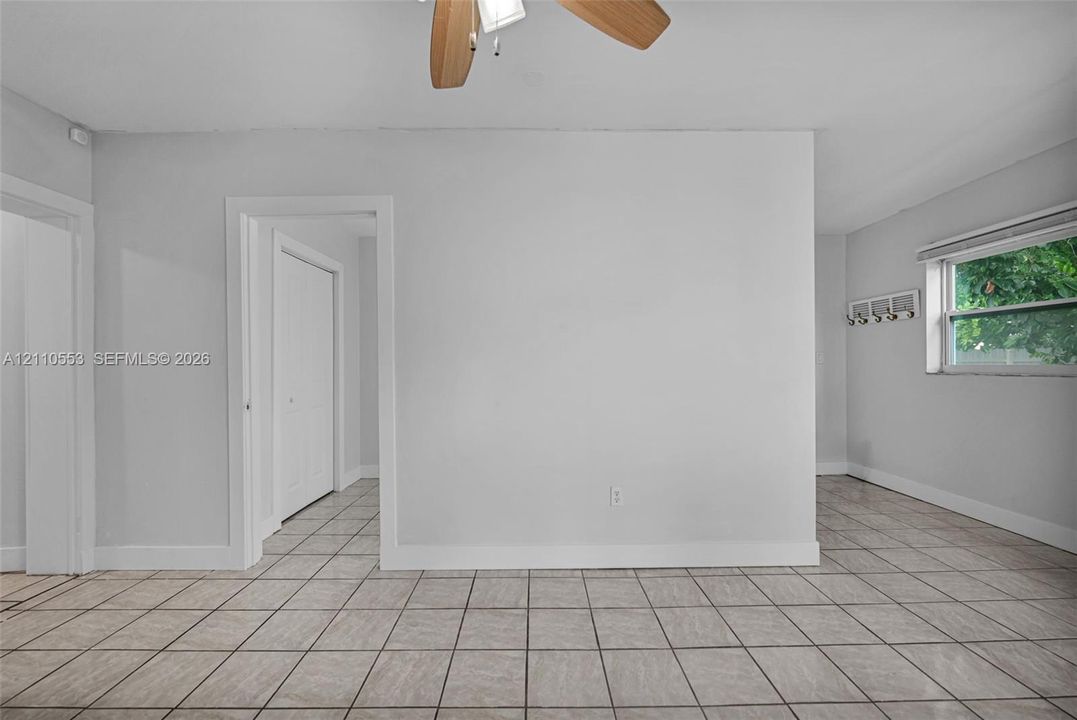 Neutral-toned interior space featuring large-format tile flooring, a ceiling fan with light fixture, and a wall-mounted hook rack