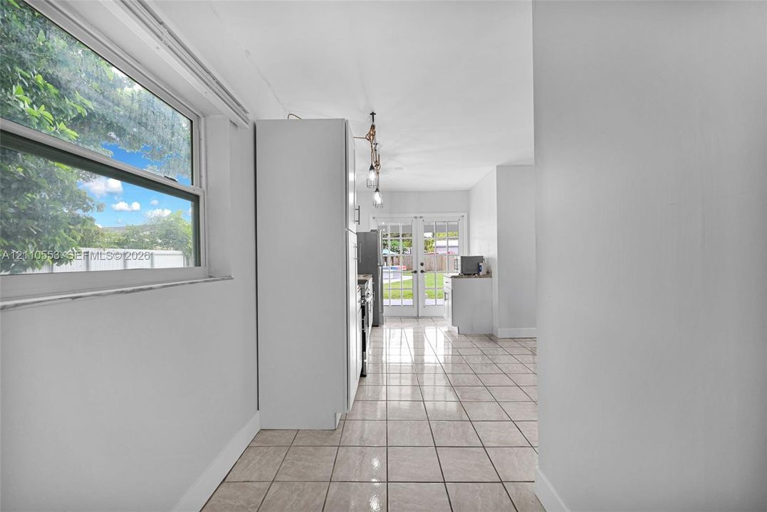 Neutral tile flooring, large single-hung window, white cabinetry, and multi-pane glass french doors