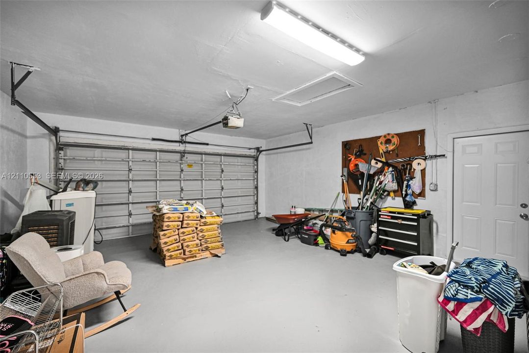 Two-car garage featuring a sectional metal door, ceiling-mounted light fixture, attic access panel, and a pedestrian service door