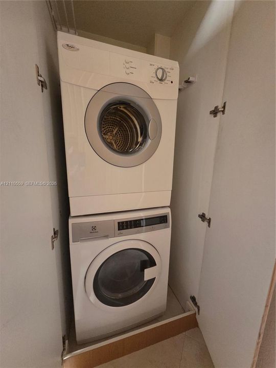 Stackable laundry unit featuring a front-loading washer and dryer housed within a dedicated closet